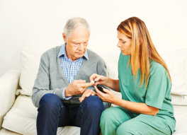 caregiver helping senior man with his medication
