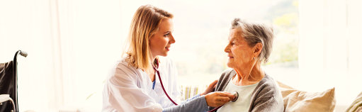 nurse with stethoscope checking senior woman