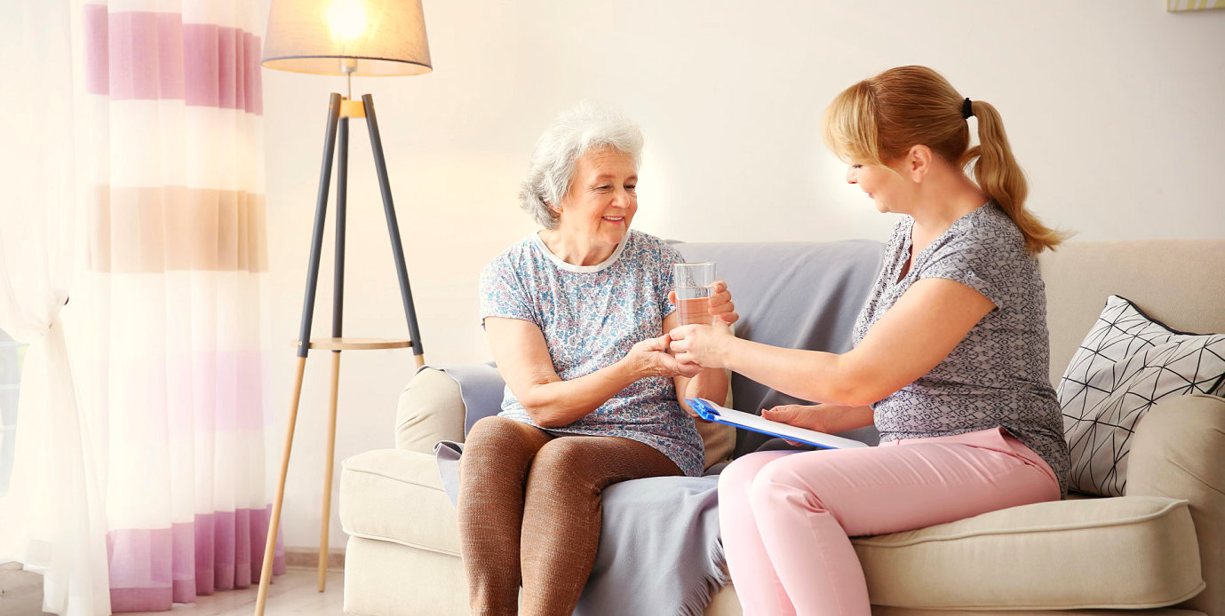 caregiver giving medication to a senior woman